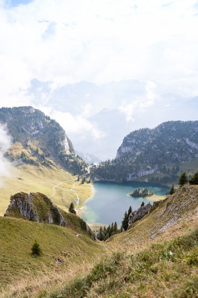 green mountains near body of water under white clouds during daytime